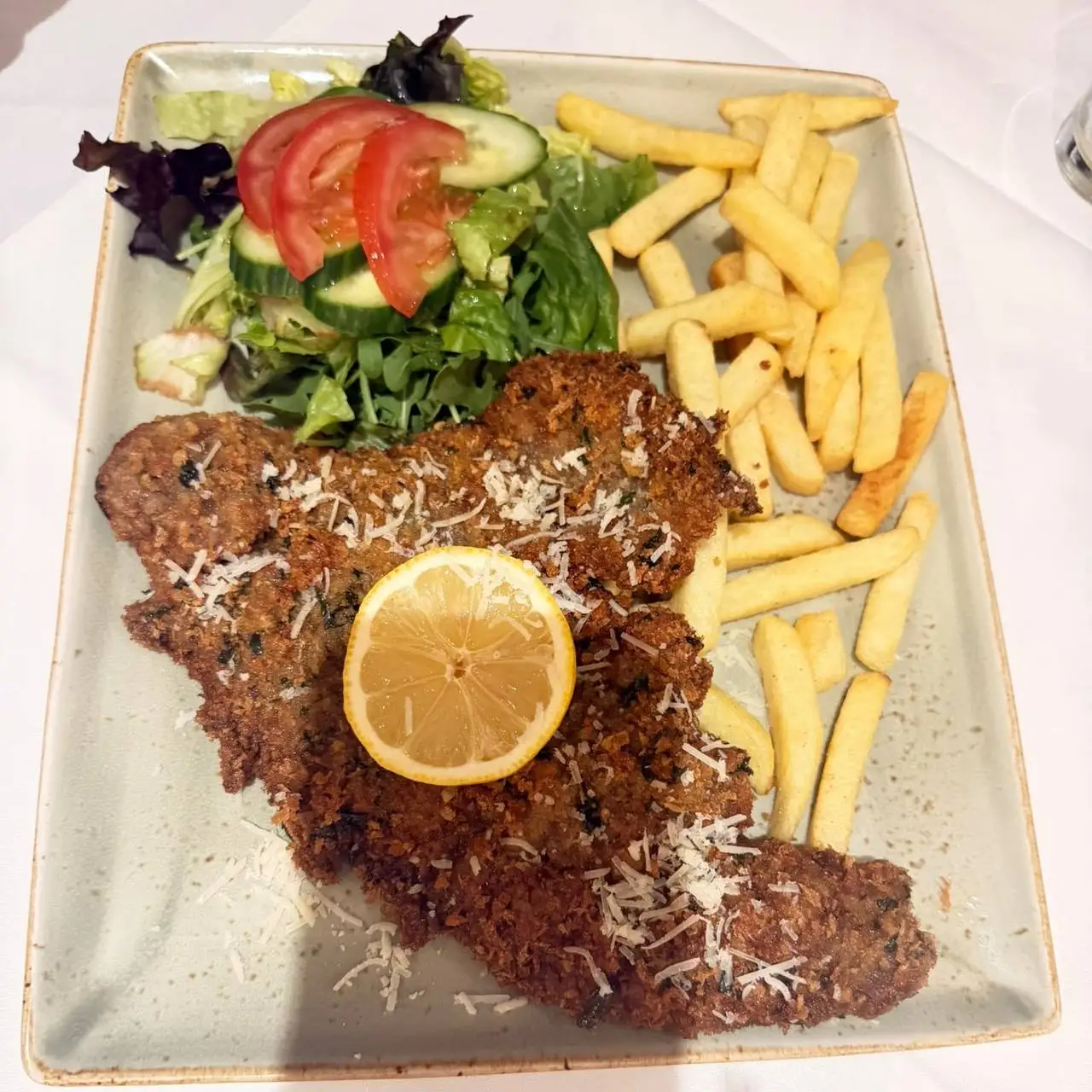 Breaded cutlet with parmesan, half a lemon, chips and salad