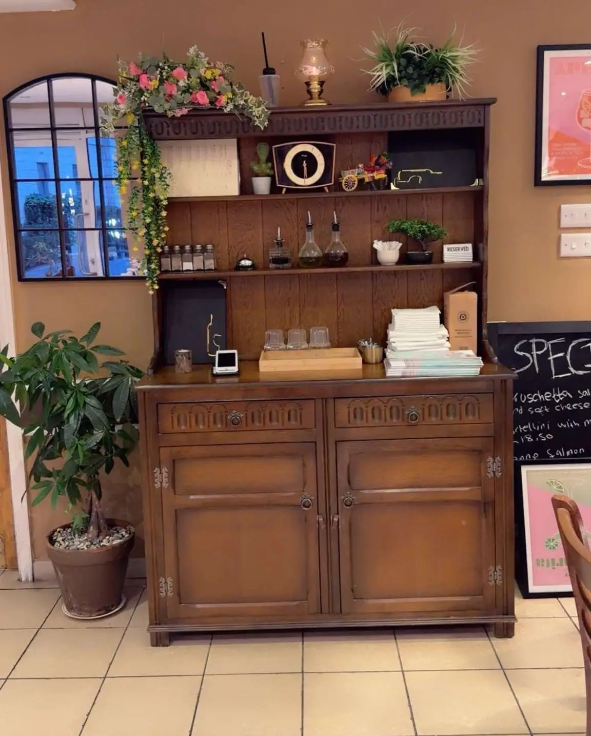 Carved oak dresser with a miniature painted Sicilian cart, olive oil, a mantel clock and flowers