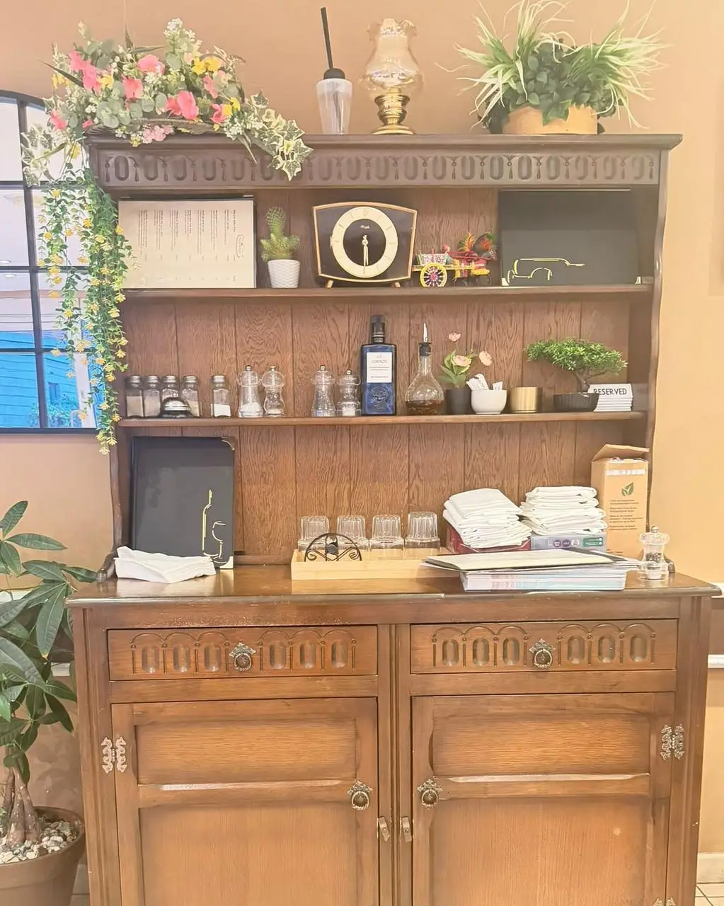 Shelves of a carved oak dresser with olive oil, a mantel clock and a miniature painted Sicilian cart