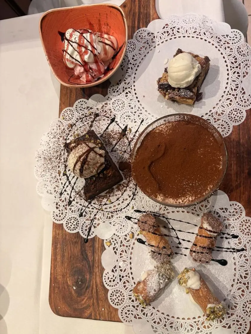 Dessert board with tiramisù, four cannoli, a brownie, a pudding and ice cream