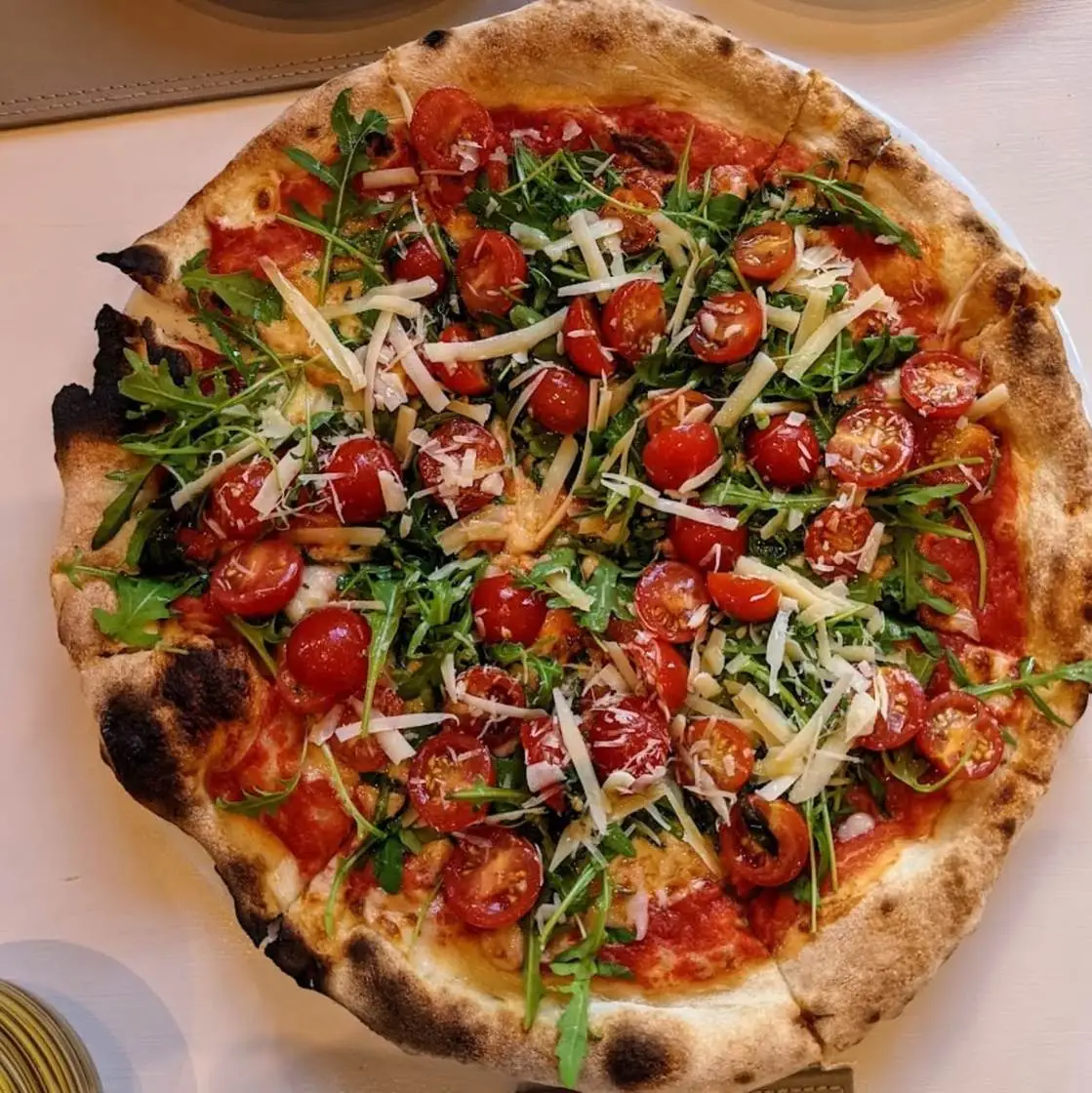 Blistered pizza with cherry tomatoes, rocket and shaved Grana