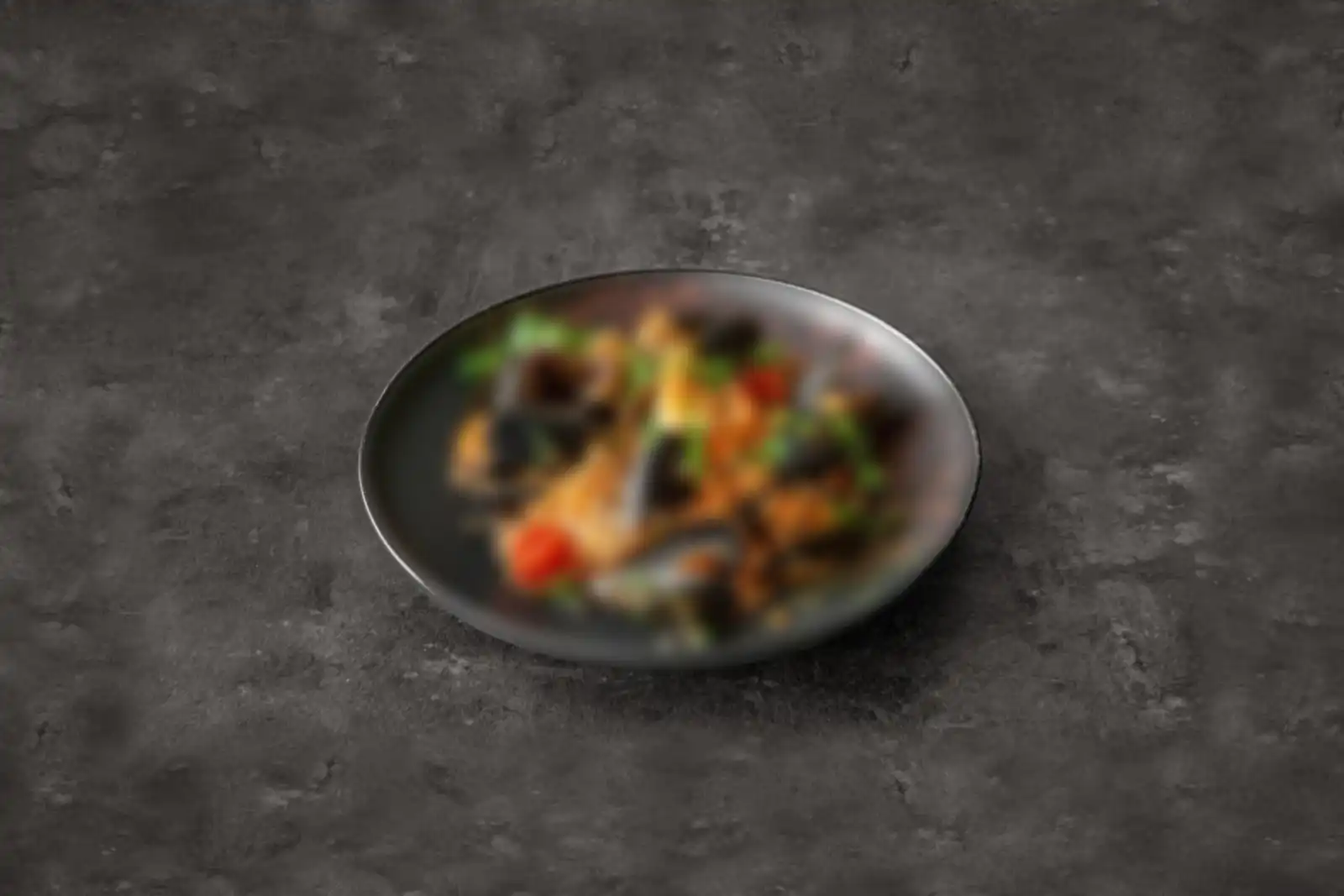 Risotto ai frutti di mare on a dark plate: mussels, a king prawn, cherry tomato and parsley
